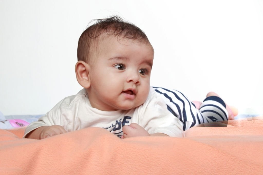 Baby doing supervised tummy time, lifting the head and looking up