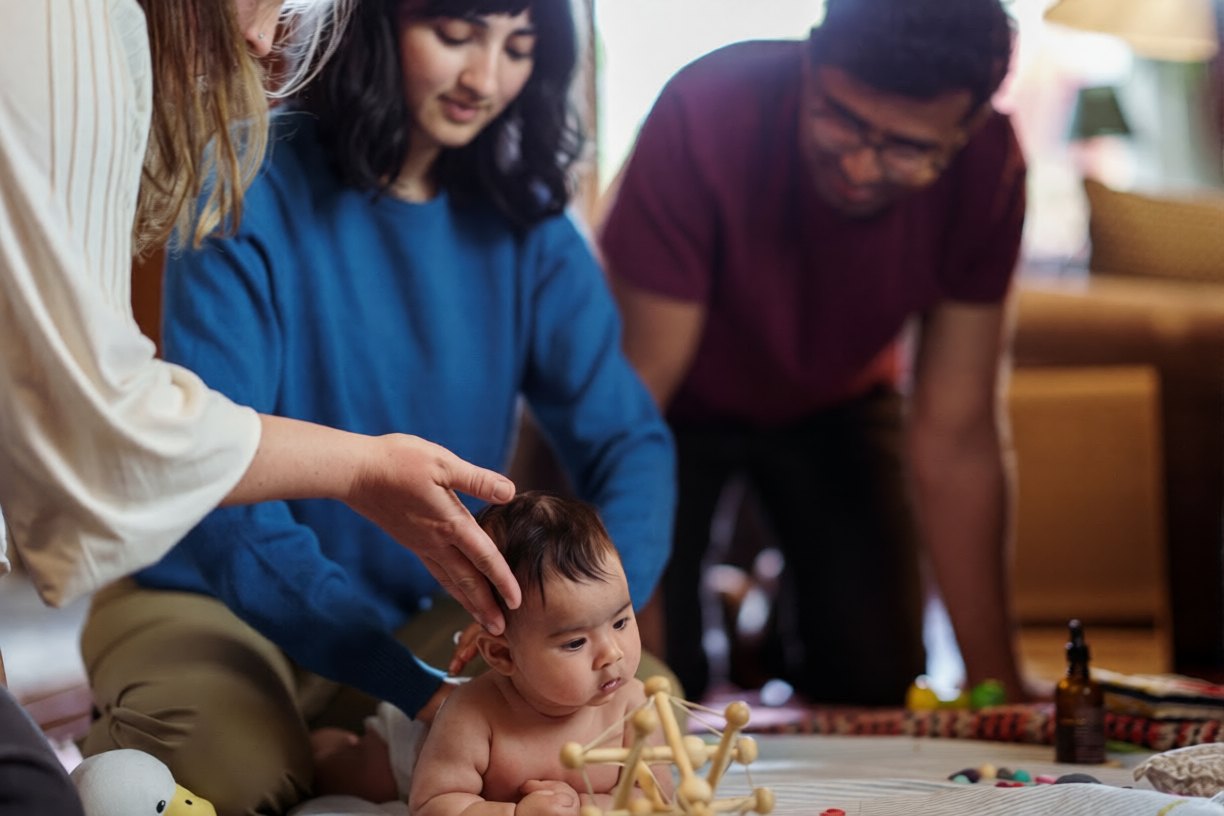 Parents and a physiotherapist playing with a baby during an in-home visit