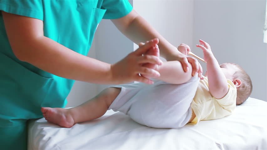 Paediatric physiotherapist gently working through a baby's leg movements on a treatment table